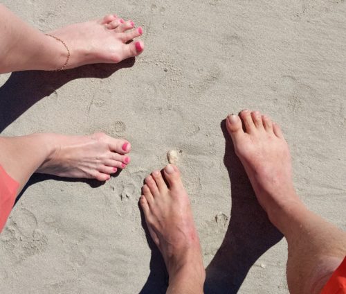 Two pairs of feet on a beach